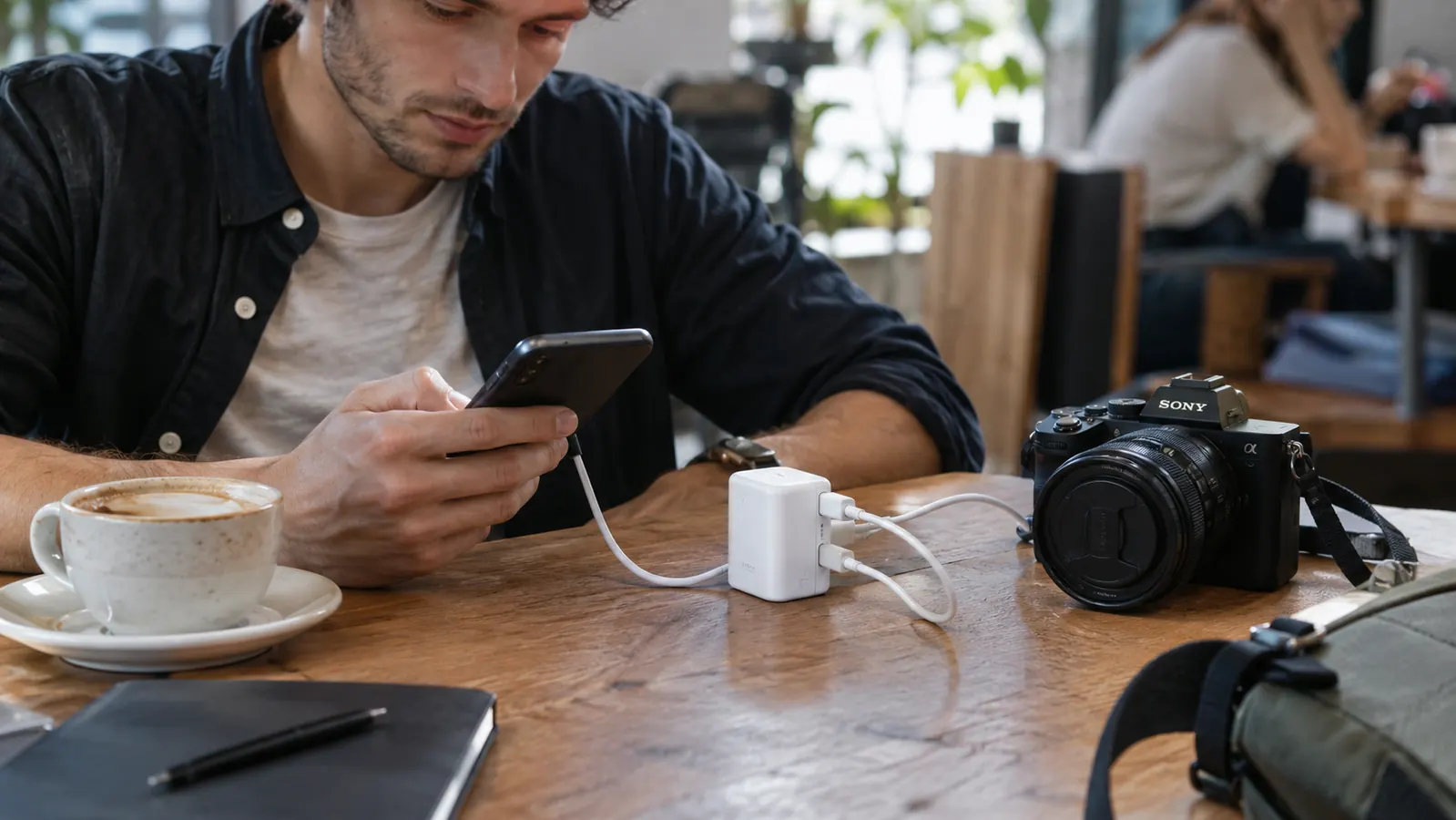 A traveler charging a phone and a camera from one adapter at a cafe table
